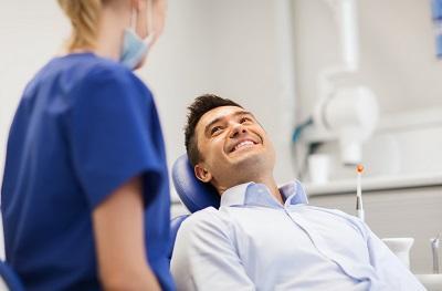 man smiling in dentist exam chair | tooth extraction rockville md