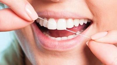 Close up of person flossing their front teeth