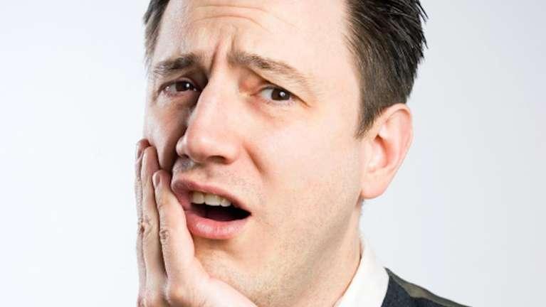 Man holding face in pain from root canal infection in Rockville, MD