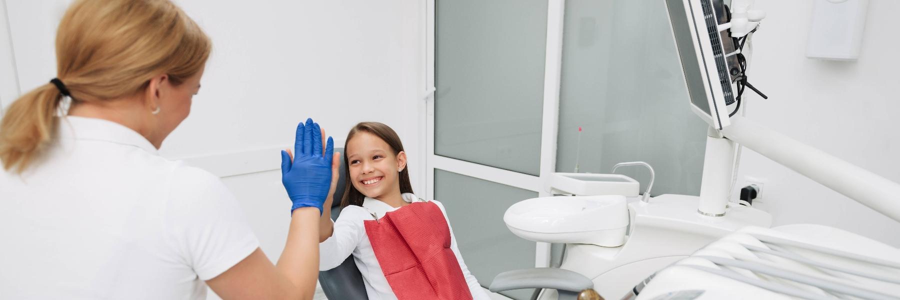 Patient in chair high-fiving children's dentist in Rockville